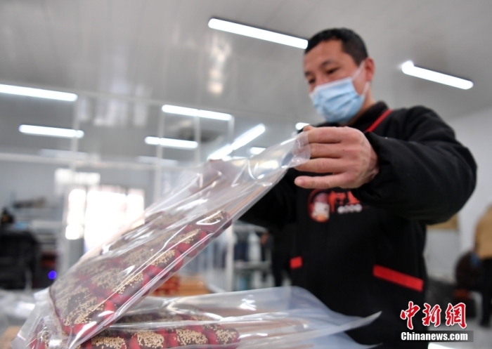 1月18日，雄安新區(qū)大樹(shù)劉莊村辛愛(ài)青家中的冰糖葫蘆加工廠，工人正對(duì)冰糖葫蘆半成品進(jìn)行真空塑封。作為遠(yuǎn)近聞名的“冰糖葫蘆村”，大樹(shù)劉莊村制作冰糖葫蘆的歷史已有100多年，全村三分之二的村民都會(huì)這門手藝，吸引不少游客慕名而來(lái)。 中新社記者 韓冰 攝